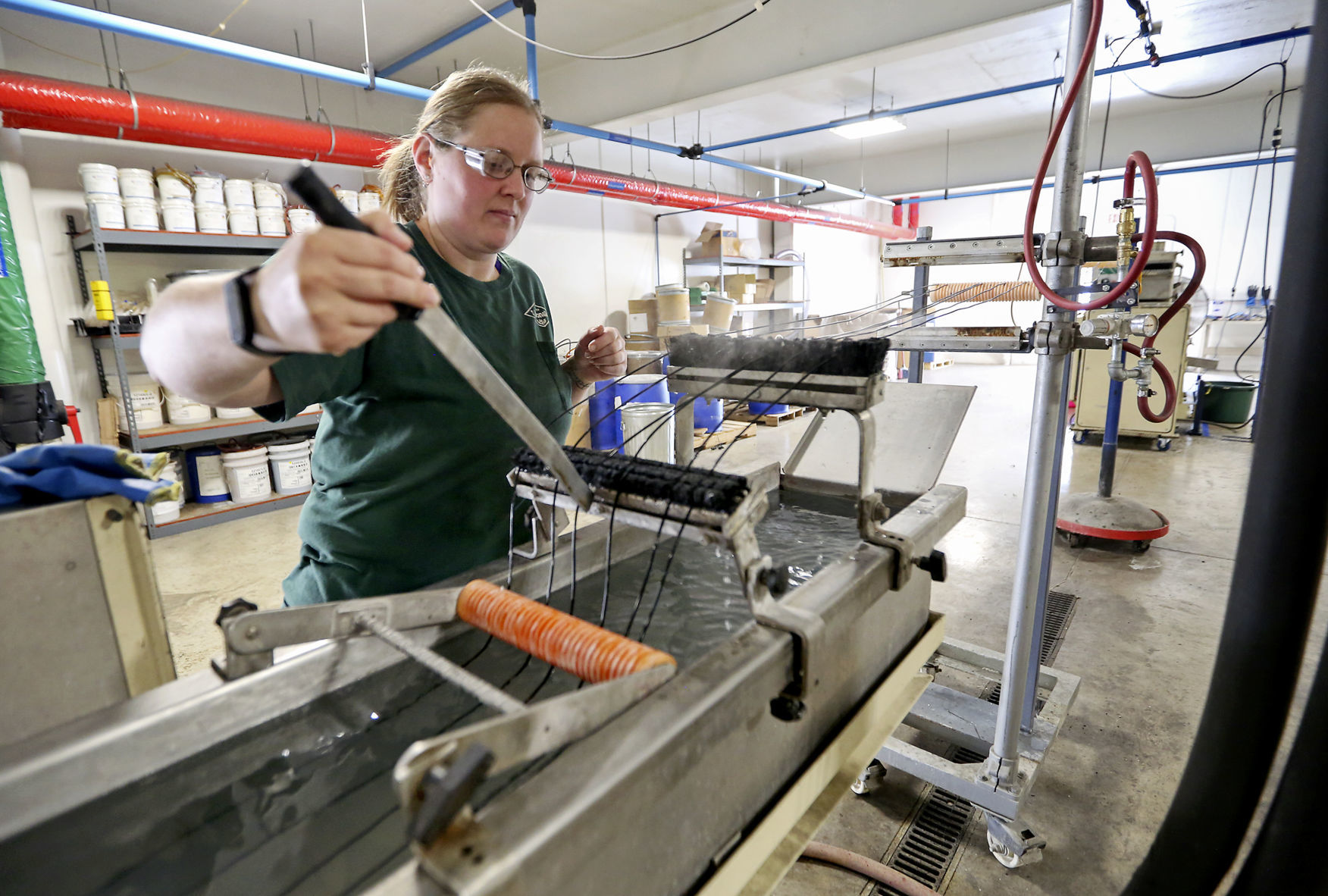 Beth Ludwig straightens strands as they run through an extrusion process at JEDA Polymers. The foundation at the Dyersville, Iowa, business is plastic pellets. However, the company adjusts the process to create specific products.    PHOTO CREDIT: NICKI KOHL