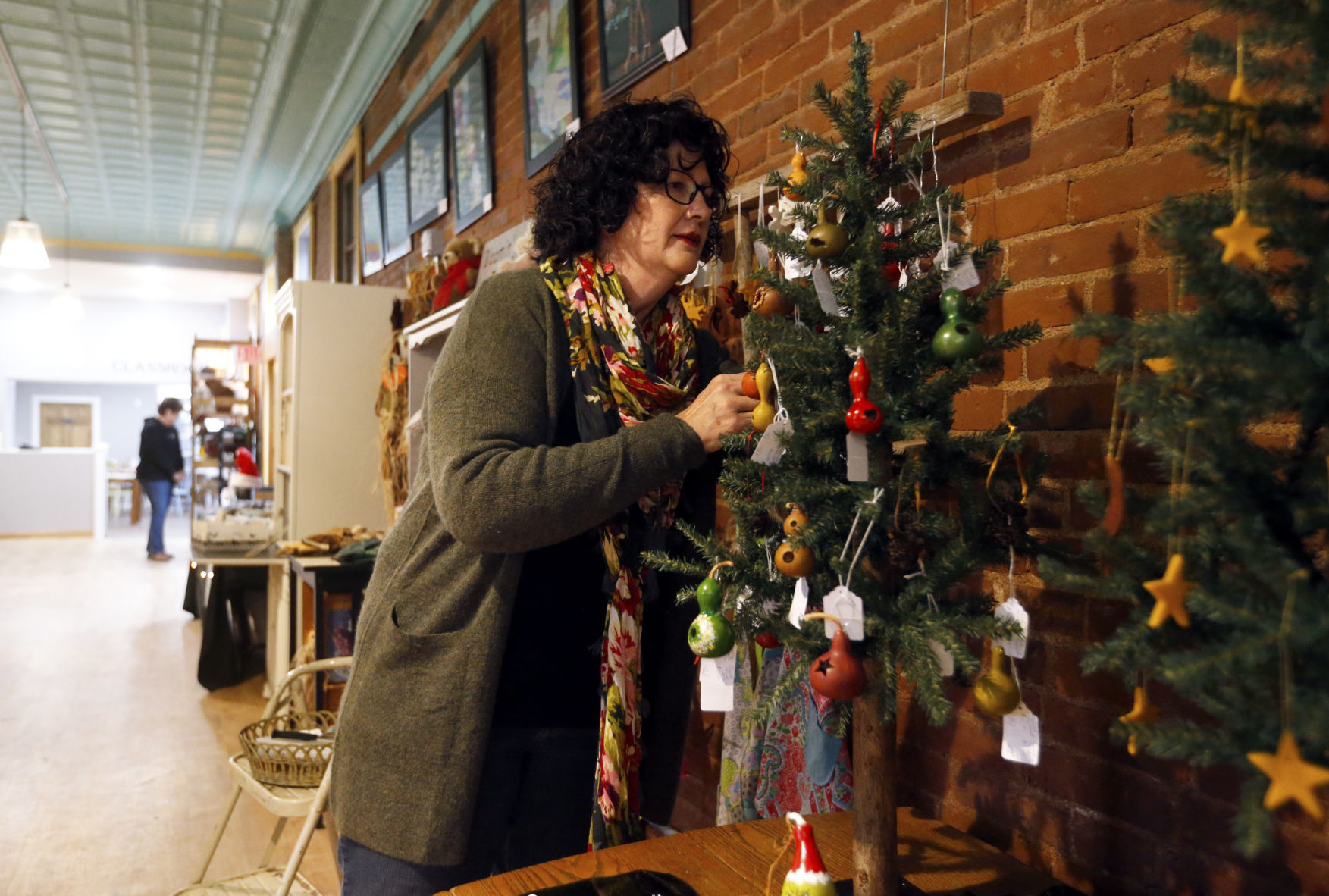 Sandra Evans, of Dubuque, displays some of her ornaments on a tree Friday at Central Avenue Mercantile in Dubuque. PHOTO CREDIT: EILEEN MESLAR