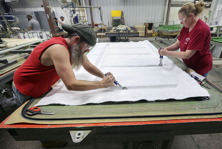 Matt Vozenilek (left) and Danielle Klosterman lay fiberglass on product.    PHOTO CREDIT: NICKI KOHL