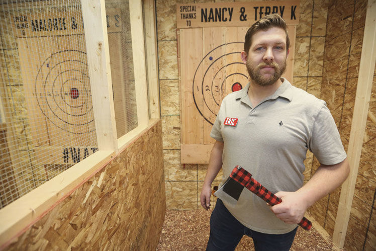 Eric Schiesl, owner of BustinAxe Throwing Range in Dubuque, stands in one of the business’s 7 throwing lanes. PHOTO CREDIT: NICKI KOHL