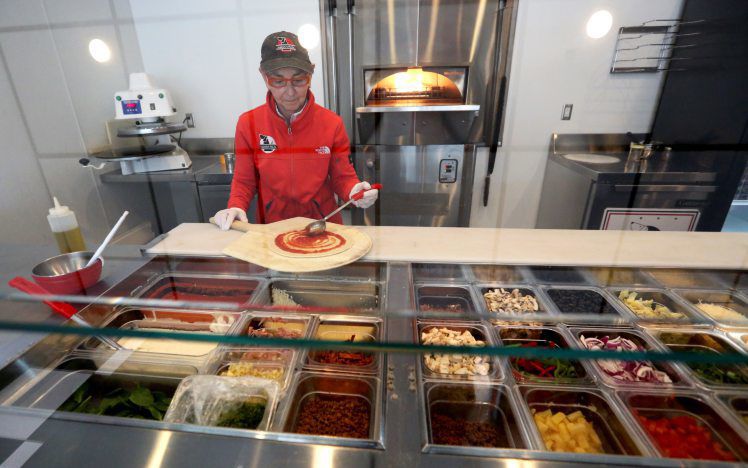 Co-owner Susan Farber prepares a pizza Friday at Magoo’s Pizza on University Avenue in Dubuque. PHOTO CREDIT: JESSICA REILLY