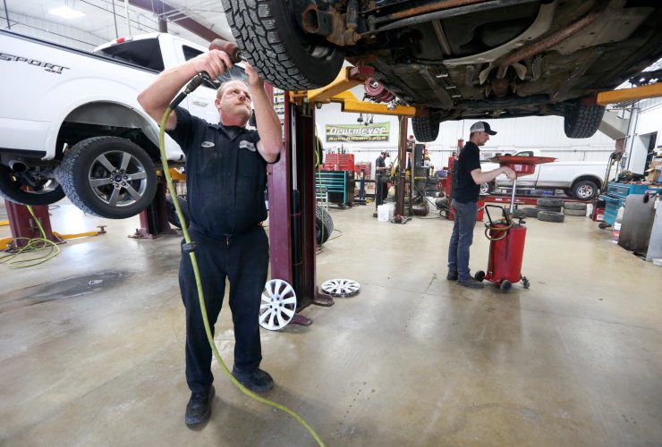 Mike Deutmeyer (left) and Sam Deutmeyer service a vehicle Friday at Deutmeyer Auto Advantage in Dyersville, Iowa. The business is offering free oil changes for health care workers and first responders. PHOTO CREDIT: NICKI KOHL