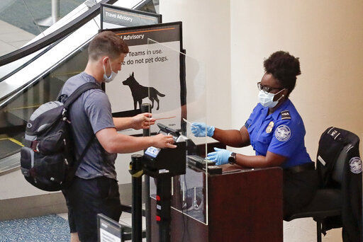 A TSA worker, right, checks a passenger before entering a security screening at Orlando International Airport Wednesday, June 17, 2020, in Orlando, Fla. Florida Gov. Ron DeSantis stated Tuesday that 52% of airport employees tested positive for COVID-19 but Phil Brown, CEO of Orlando International Airport, said in a statement Wednesday that last week