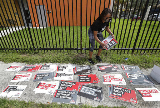 Kelli Ann Thomas, a candidate for Community Council, sorts signs before the start of a Workers First Caravan, Wednesday, June 17, 2020, in Miami. The caravan was part of a nation-wide effort to urge those in government to implement policies that further economic and racial justice. (AP Photo/Wilfredo Lee) PHOTO CREDIT: Wilfredo Lee