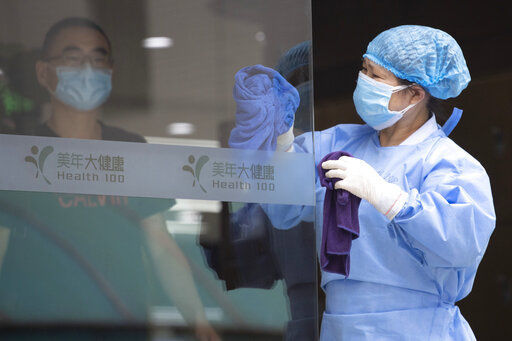 A worker cleans the glass door to a health center for COVID-19 testing in Beijing on Wednesday, June 17, 2020. The Chinese capital on Wednesday canceled more than 60% of commercial flights and raised the alert level amid a new coronavirus outbreak, state-run media reported. (AP Photo/Ng Han Guan) PHOTO CREDIT: Ng Han Guan