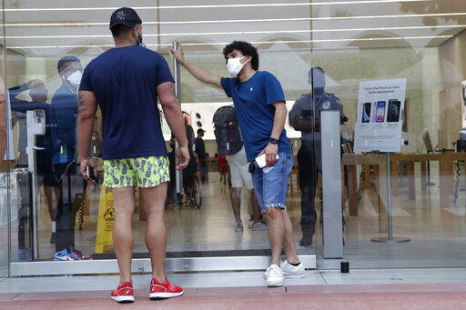 An employee wearing a protective face covering, right, monitors the flow of customers at an Apple retail store along Lincoln Road Mall during the new coronavirus pandemic, Wednesday, June 17, 2020, in Miami Beach, Fla. (AP Photo/Lynne Sladky) PHOTO CREDIT: Lynne Sladky