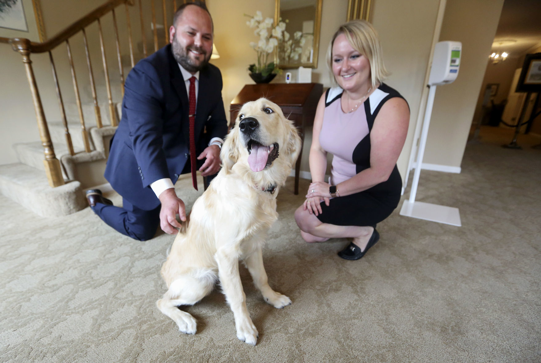 Managing Funeral Director Scott Glover and Office Manager Samantha Glover play with their dog, Stanley, at Hoffmann Schneider & Kitchen Funeral Home and Cremation Service in Dubuque, on Friday, June 19, 2020. Stanley is an English golden retriever and comes to the business to provide stress relief for employees and customers. PHOTO CREDIT: NICKI KOHL