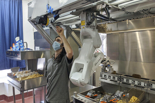 A technician makes an adjustment to a robot at Miso Robotics