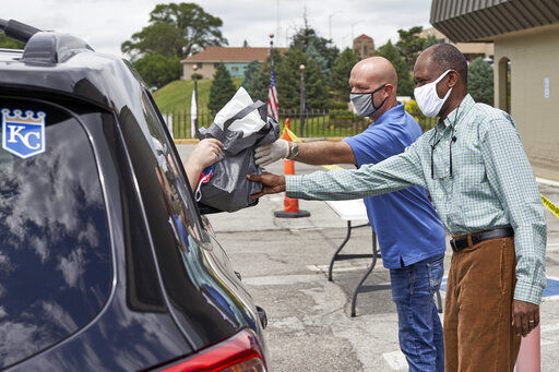 A motorist is handed a bag containing information about open positions at a drive-thru job fair in Omaha, Neb., Wednesday, July 15, 2020. Nebraska reinstated job search requirements this week for most people claiming jobless benefits. Those unemployment insurance requirements were suspended in mid-March to help employees who had lost their jobs due to the coronavirus. (AP Photo/Nati Harnik) PHOTO CREDIT: Nati Harnik