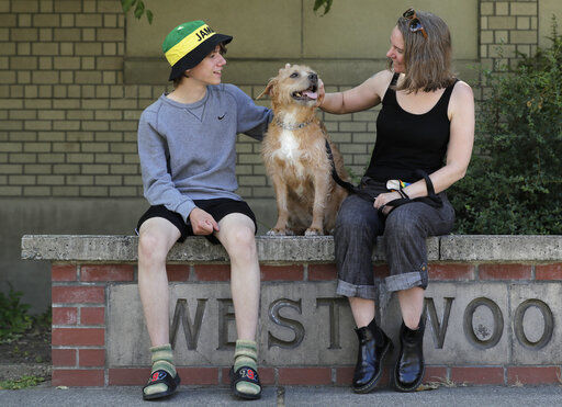 Jennifer Haller, right, the first person to receive a trial dose of a COVID-19 vaccine, poses for a photo with her son Hayden, 16, and their dog Meg, Sunday, July 19, 2020, in Seattle. As the world