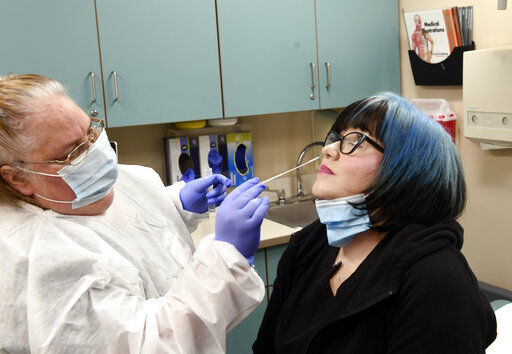 Nurse Jen Molstead, left, gives volunteer Melissa Harting of Harpersville, N.Y., a nasal swab test as the world