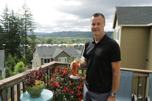 Neal Browning, the second person to receive a trial dose of a COVID-19 vaccine, poses for a photo holding a hummingbird feeder, Friday, July 24, 2020, in Bothell, Wash. As the world