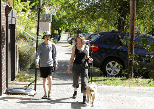 Jennifer Haller, right, the first person to receive a trial dose of a COVID-19 vaccine, walks with her son Hayden, 16, and their dog Meg, Sunday, July 19, 2020, in Seattle. As the world