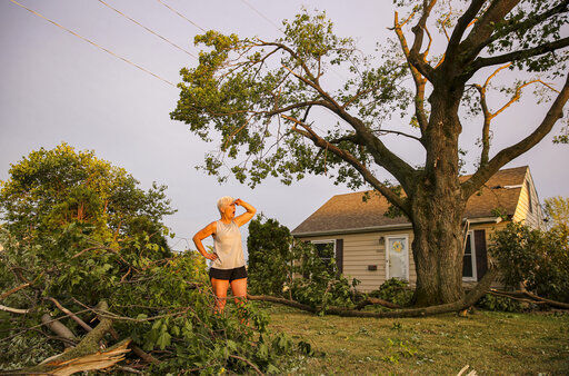 Laurie Berdahl stands in her front yard Wednesday beginning to clean up downed limbs around her home in Cedar Rapids, Iowa. Hundreds of thousands of residents in Iowa’s three largest cities remained without electricity, two days after a rare wind storm devastated the state’s power grid, flattened corn fields and killed two people. PHOTO CREDIT: Andy Abeyta