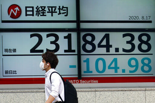 A man walks past an electronic stock board showing Japan