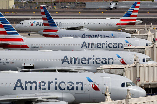 FILE - In this March 25, 2020, file photo, American Airlines jets sit idly at their gates as a jet arrives at Sky Harbor International Airport in Phoenix. American Airlines is telling 25,000 workers that they could lose their jobs in October because of the sharp drop in air travel during the virus pandemic. The airline said Wednesday, July 15, it was starting new offers of buyouts and partially paid leave, which it hopes will reduce the number of furloughs. (AP Photo/Matt York, File) PHOTO CREDIT: Matt York
