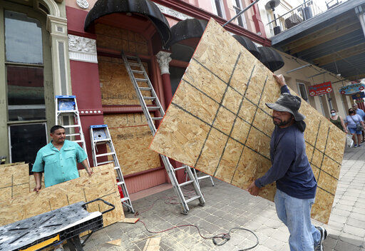 Cesar Reyes (right) carries a sheet of plywood to cut to size as he and Robert Aparicio install window coverings at Strand Brass and Christmas in Galveston, Texas. Tropical Storm Laura entered the warm and deep waters of the Gulf of Mexico today, gathering strength on a path to hit the U.S. coastline early Thursday as a major hurricane. PHOTO CREDIT: Jennifer Reynolds