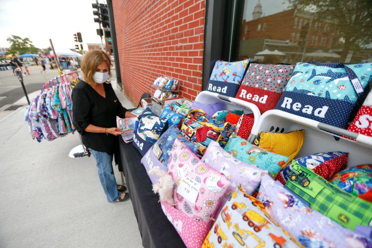 Iris Encke owner of Bloomin’ Iris sets up her products at the farmers market in Dubuque. Encke started the business in 2009 after retiring from the Dubuque Community School District. She creates baby items, clothing and other products. PHOTO CREDIT: Dave Kettering