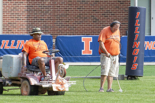 University of Illinois athletic facility attendants Tyrone Washington, left, and Shawn Hannan, right, renew the line markers of the schools football practice field in Champaign, Ill., Wednesday, Sept. 16, 2020. Less than five weeks after pushing fall sports to spring in the name of player safety during the pandemic, the Big Ten conference changed course Wednesday and said it plans to open its football season the weekend of Oct. 23-24. (Robin Scholz/The News-Gazette via AP) PHOTO CREDIT: Robin Scholz