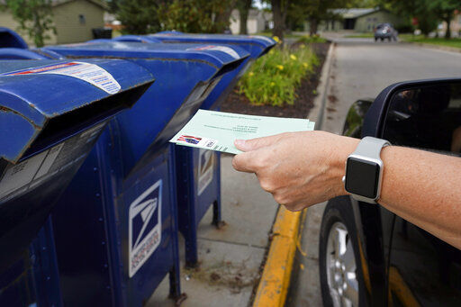 FILE - In this Tuesday, Aug. 18, 2020, file photo, a person drops applications for mail-in-ballots into a mailbox in Omaha, Neb. Data obtained by The Associated Press shows Postal Service districts across the nation are missing the agency’s own standards for on-time delivery as millions of Americans prepare to vote by mail. (AP Photo/Nati Harnik, File) PHOTO CREDIT: Nati Harnik