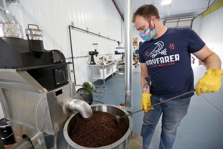 Darin Shireman moves around roasted coffee beans at Wayfarer Coffee in Dubuque. He promotes ethical sourcing of the beans, which encourages a fair price for the growers and a better product. Shireman also has developed a roasting process with his specialized machinery.    PHOTO CREDIT: JESSICA REILLY