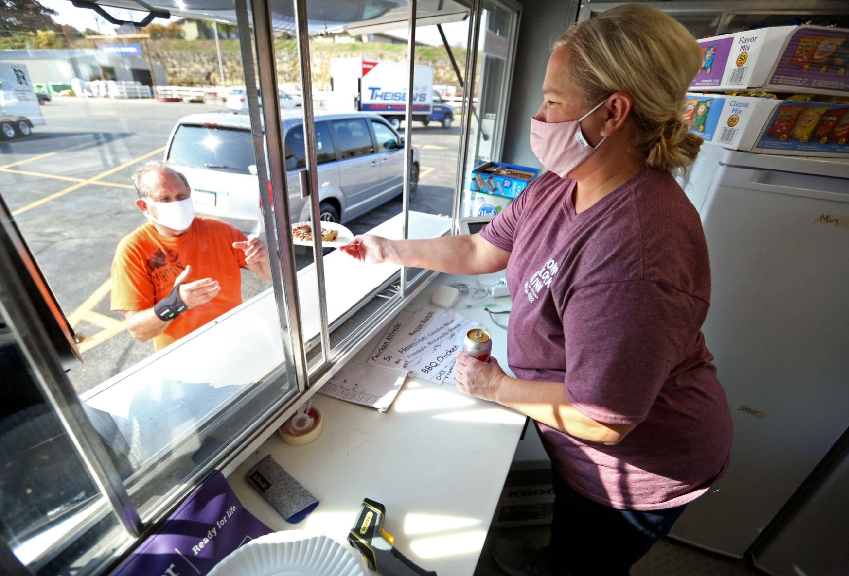 Town Clock Inn co-owner Irene Nelson serves pizza from a food truck at Theisen’s Home-Farm-Auto in Dubuque on Sunday. The longtime downtown restaurant is taking its business to customers as the pandemic drags on. PHOTO CREDIT: JESSICA REILLY