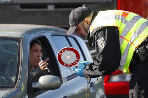 A German police officer checks authorization for a woman to enter Germany at the German-France border in Kehl, Germany. European Union countries are set to adopt a common traffic light system to coordinate traveling across the 27-nation bloc, but a return to a full freedom of movement in the midst of the COVID-19 pandemic remains far from reach.  PHOTO CREDIT: Jean-Francois Badias
