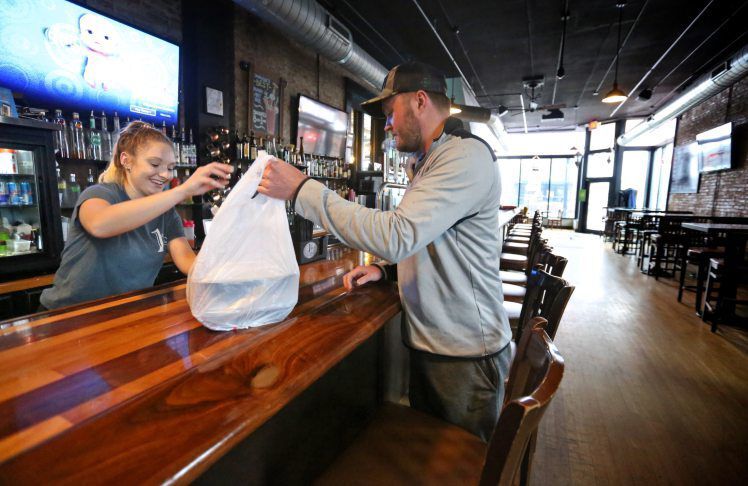 Jared Sweeney, of Dubuque, picks up food from Kayla DeMoss at 1st & Main in Dubuque on Thursday, March 19, 2020. The dine-in area of the restaurant is closed through March 31 in response to the COVID-19 pandemic, but the business remains open for carryout orders. PHOTO CREDIT: TH file