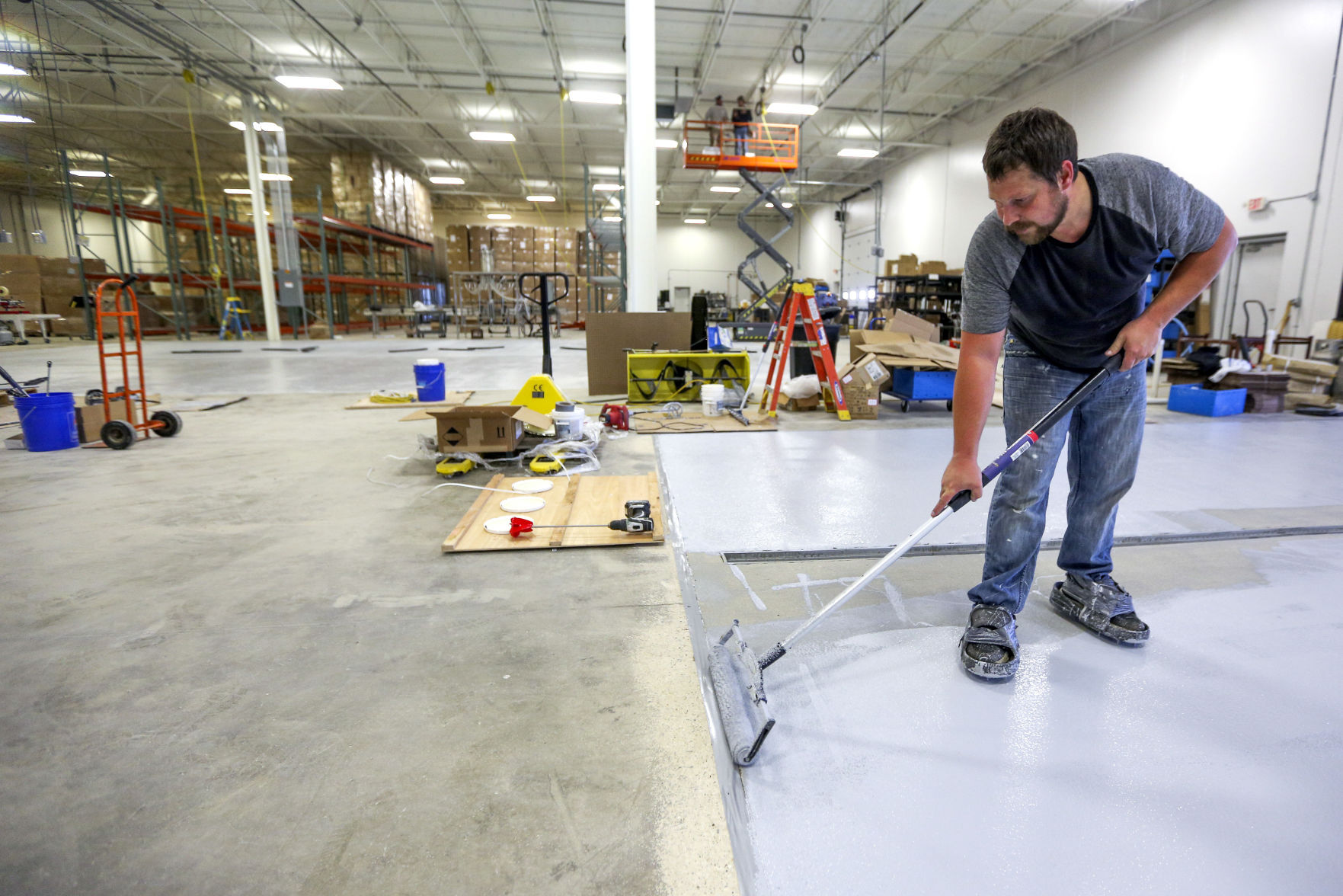 Lance Hummel, owner of Higley Industries Inc., seals the floor of his new building on Industrial Parkway Southwest in Dyersville, Iowa, on Thursday. The company has seen business booming during the pandemic. PHOTO CREDIT: Dave Kettering