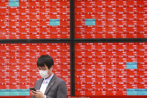 A man walks by an electronic stock board of a securities firm in Tokyo. Shares advanced in Asia today after China reported its economy grew at a 4.9% annual pace in the last quarter, with consumer spending and industrial production rising to pre-pandemic levels. Stocks are edging higher on Wall Street at the beginning of another busy week for corporate earnings news. PHOTO CREDIT: Koji Sasahara
