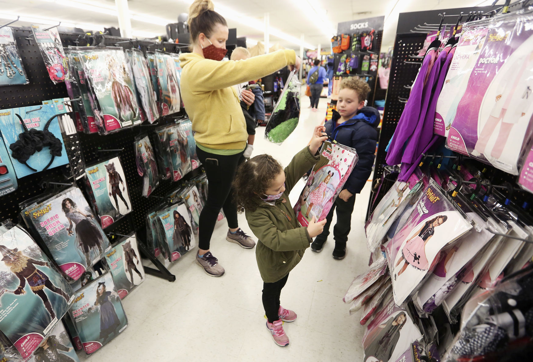 Carrie Johnson (from left), Evelyn Johnson, 3, and Braxton Johnson, 4, all of Dyersville, Iowa, browse costumes at Spirit Halloween in Dubuque on Tuesday, Oct. 20, 2020. PHOTO CREDIT: NICKI KOHL