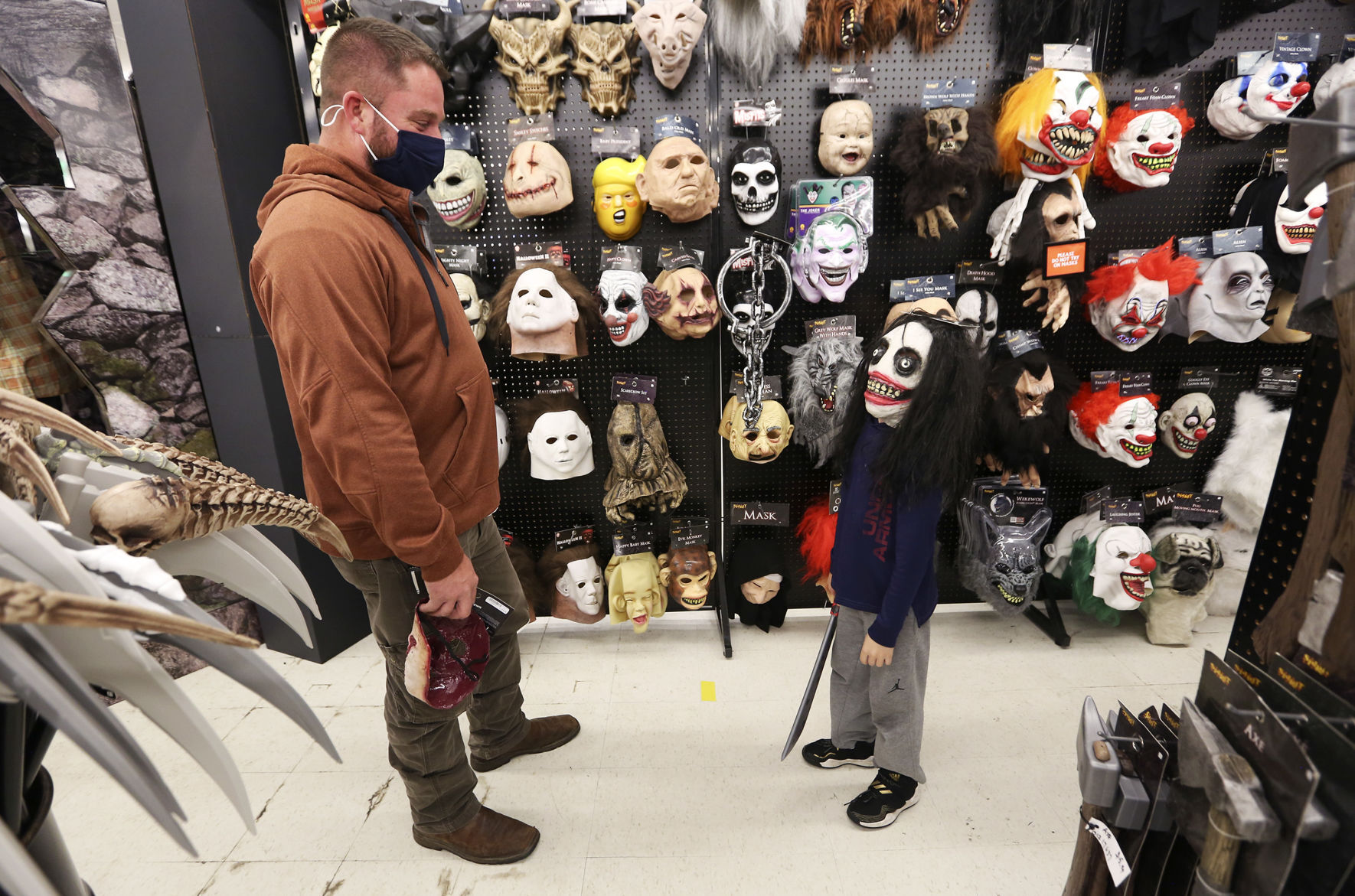 Drexel Thole, 7, shows off a mask to Jadyn Thole, of La Motte, Iowa, while shopping at Spirit Halloween in Dubuque on Tuesday. Local retailers report strong interest in Halloween-related merchandise this year. PHOTO CREDIT: NICKI KOHL