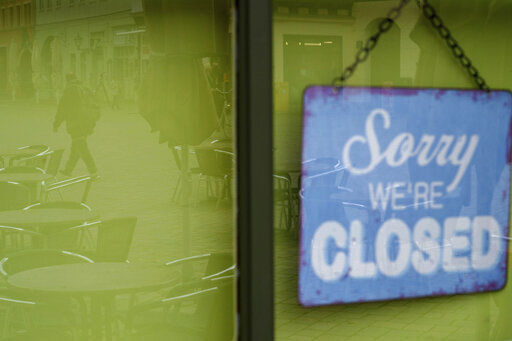 "Sorry we re closed" is written on a sign hanging on the door of a coffee shop where the unoccupied tables and chairs are reflected in the glass pane in Quedlinburg, Germany, Monday, Nov.2, 2020. Since midnight the four-week partial lockdown has been in effect in Saxony-Anhalt. The federal and state governments want to significantly reduce social contacts in Germany in November in order to get a grip on the recently rapidly increasing corona numbers before the Advent season if possible. (Klaus-Dietmar Gabbert/dpa via AP) PHOTO CREDIT: Klaus-Dietmar Gabbert