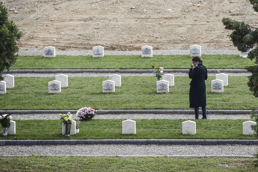 A woman pays tribute to a tomb in the field 87 of the Maggiore cemetery, where several unclaimed victims of the COVID-19 pandemic were buried, in the day devoted to remembrance of the departed, in Milan, Italy, Monday, Nov. 2, 2020. (AP Photo/Luca Bruno) PHOTO CREDIT: Luca Bruno