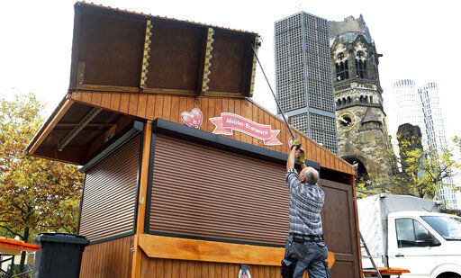 Due to the new coronavirus lockdown a Christmas market trader builds down a market booth at the Breitscheidt square close to the Kaiser Wilhelm Memorial Church, right, in Berlin, Germany, Monday, Nov. 2, 2020. (AP Photo/Michael Sohn) PHOTO CREDIT: Michael Sohn