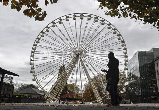 A man passes a closed Ferris wheel in the city center of Essen, Germany, Monday, Nov. 2, 2020. A one month long partial lockdown due to the coronavirus pandemic becomes effective in Germany on Monday. (AP Photo/Martin Meissner) PHOTO CREDIT: Martin Meissner