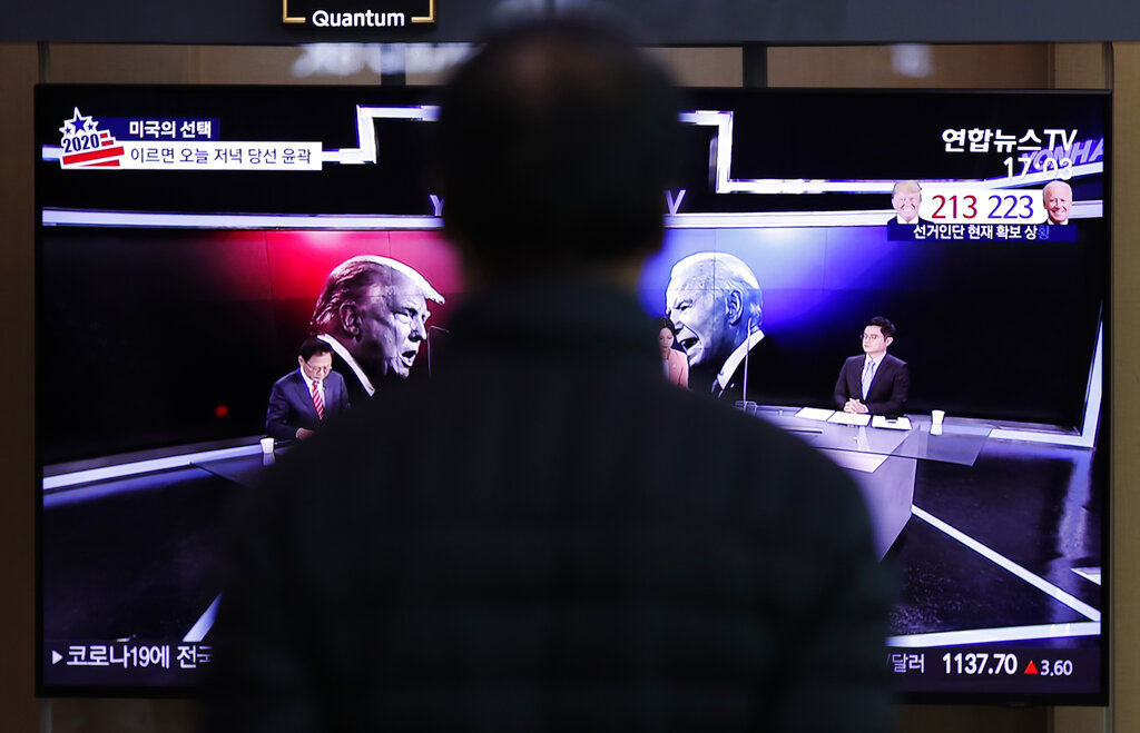 A man watches a TV screen showing the images of U.S. President Donald Trump and Democratic presidential candidate former Vice President Joe Biden during a news program of the U.S. presidential election in Seoul, South Korea. Without an immediate result, the guessing game of trying to figure out whether — and how —Trump or Biden would end up in the White House quickly turned global. PHOTO CREDIT: Lee Jin-man