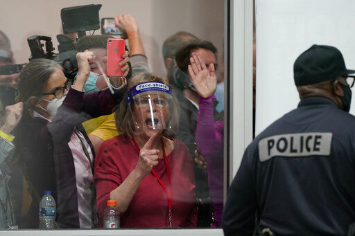 Election challengers yell as they look through the windows of the central counting board as police were helping to keep additional challengers from entering due to overcrowding, Wednesday, Nov. 4, 2020, in Detroit. (AP Photo/Carlos Osorio) PHOTO CREDIT: Carlos Osorio