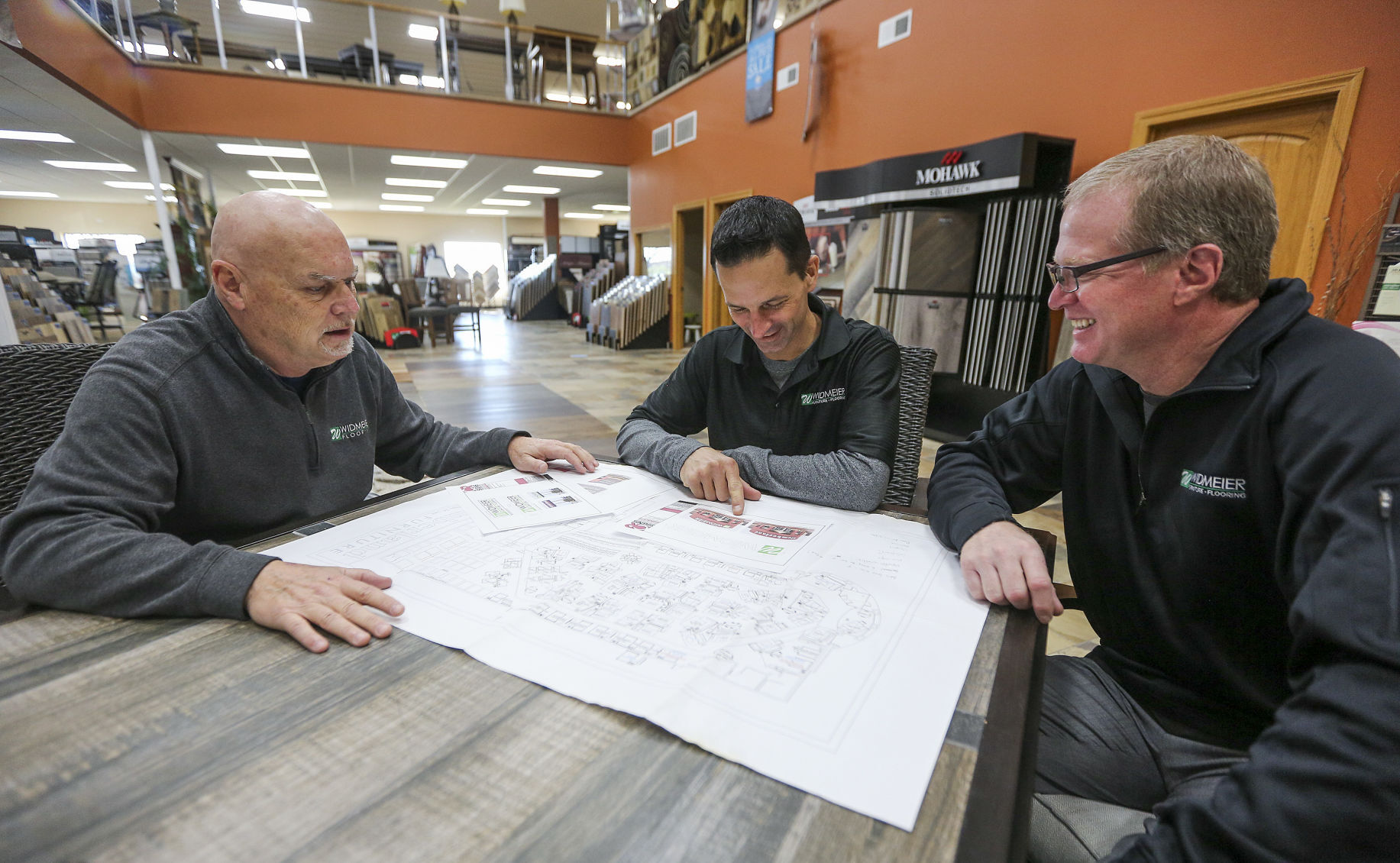 Joe Widmeier (center) along with his employees Brian Blodgett (left) and Bob Duax look over the plans for the new location of the Dubuque store. PHOTO CREDIT: Dave Kettering