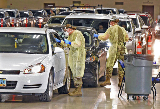 FILE - In this Nov. 17, 2020, file photo, North Dakota National Guard soldiers Spc. Samantha Crabbe, left, and Master Sgt. Melanie Vincent administer COVID-19 tests inside the Bismarck Events Center in Bismarck, N.D. With coronavirus cases surging and families hoping to gather safely for Thanksgiving, long lines to get tested have reappeared across the U.S. (Tom Stromme/The Bismarck Tribune via AP, File) PHOTO CREDIT: Tom Stromme