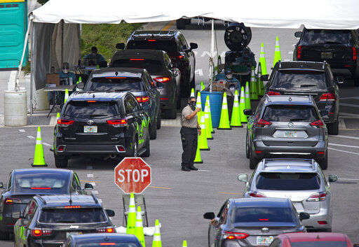 FILE - In this Nov. 18, 2020, file photo, vehicles line up as healthcare workers assist to check in citizens to be tested at the COVID-19 drive-thru testing center at Miami Beach Convention Center in Miami Beach, Fla. With coronavirus cases surging and families hoping to gather safely for Thanksgiving, long lines to get tested have reappeared across the U.S. (David Santiago/Miami Herald via AP, File) PHOTO CREDIT: David Santiago