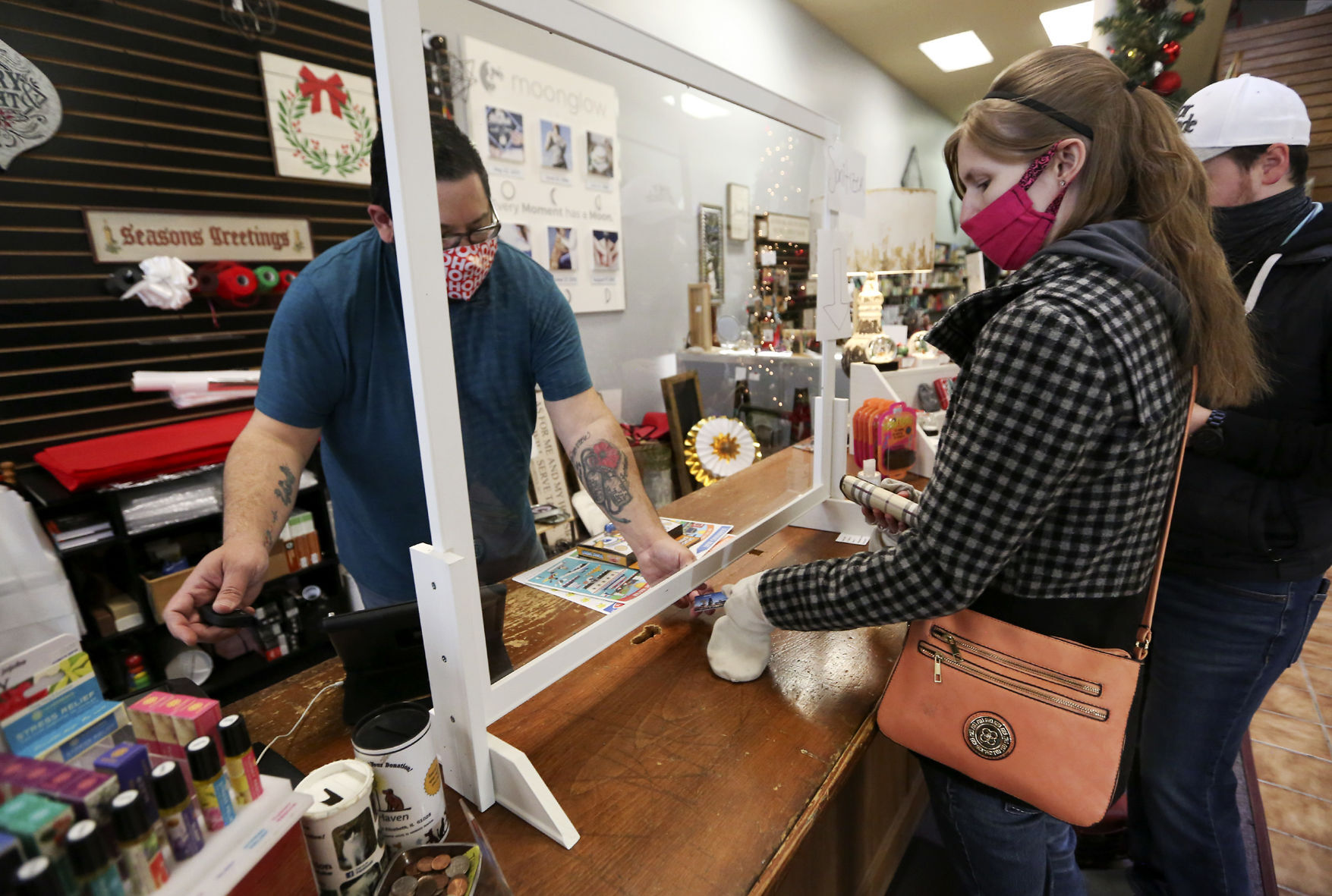 Steven Gonzalez (from left) completes a transaction for Holly Koenig and Matthew Koenig, both of Rockford, Ill., at Gabby’s Gifts in Galena, Ill., on Friday. Retailers in Galena are cautiously optimistic as Thanksgiving weekend approaches. PHOTO CREDIT: NICKI KOHL, Telegraph Herald
