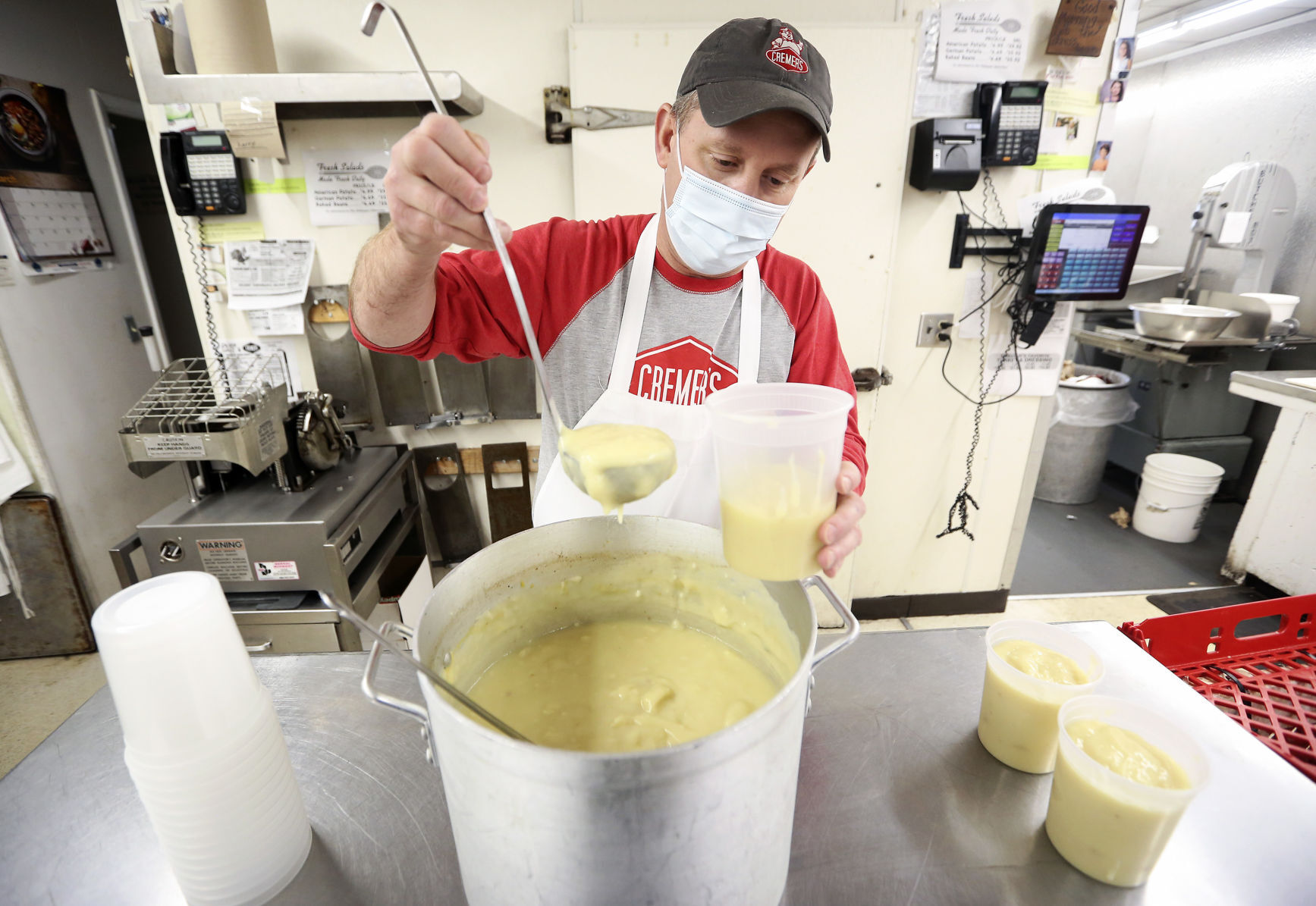 Jeff Cremer fills to-go containers of homemade turkey gravy at Cremer’s Meats in Dubuque on Monday. PHOTO CREDIT: NICKI KOHL