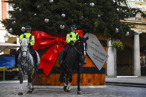 Two police officers ride their horses backdropped by a Christmas tree in Covent Garden, in London, Tuesday, Nov. 24, 2020. Haircuts, shopping trips and visits to the pub will be back on the agenda for millions of people when a four-week lockdown in England comes to an end next week, British Prime Minister Boris Johnson said Monday. (AP Photo/Alberto Pezzali) PHOTO CREDIT: Alberto Pezzali