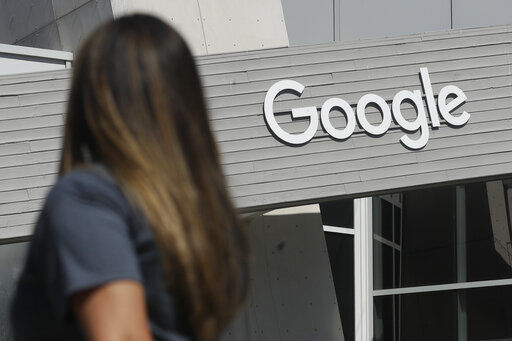 FILE - In this Sept. 24, 2019, file photo a woman walks below a Google sign on the campus in Mountain View, Calif. In the years since Barack Obama and Joe Biden left the White House, the tech industry