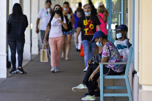 Shoppers wear protective face masks as they look for Black Friday deals at the Ellenton Premium Outlet stores Friday, Nov. 27, 2020, in Ellenton, Fla. Attendance at the mall was down in an attempt to avoid spreading the corona virus. (AP Photo/Chris O