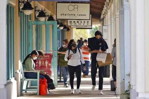 Shoppers wear protective face masks as they look for Black Friday deals at the Ellenton Premium Outlet stores Friday, Nov. 27, 2020, in Ellenton, Fla. Attendance at the mall was down in an attempt to avoid spreading the corona virus. (AP Photo/Chris O