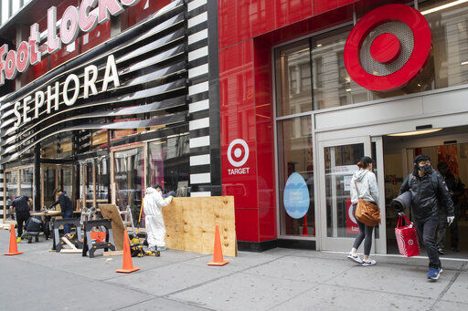 FILE - In this Friday, March 20, 2020 file photo, a shopper leaves the Target Store on 34th St. with supplies as carpenter board up the Sephora story in New York. Target Corp. said Friday it will give a $2 an hour wage increase to its 300,000-plus workers who have been scrambling to help customers. The pay bump will be effective at least through May 2. (AP Photo/Mary Altaffer, File) PHOTO CREDIT: Mary Altaffer