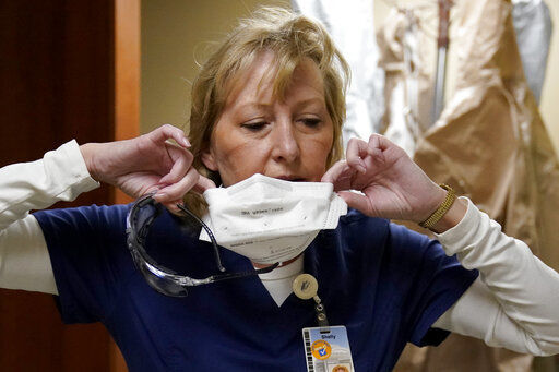 FILE - In this Nov. 24, 2020, file photo, marks are seen on the face of registered nurse Shelly Girardin as she removes a protective mask after performing rounds in a COVID-19 unit at Scotland County Hospital in Memphis, Mo. Across the U.S., the surge has swamped hospitals with patients and left nurses and other health care workers shorthanded and burned out. (AP Photo/Jeff Roberson) PHOTO CREDIT: Jeff Roberson