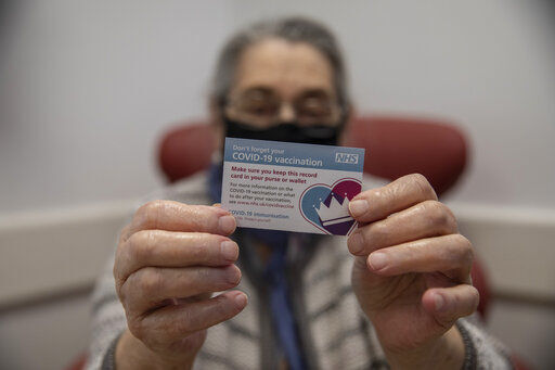 Bernice Wainer, 82, holds her vaccination record card after she was vaccinated at Royal Free hospital in north London on the first day of the largest immunization program in the UK